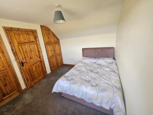 a small bedroom with a bed and wooden doors at Beacon View, Church Cross, Skibbereen, County Cork in Church Cross