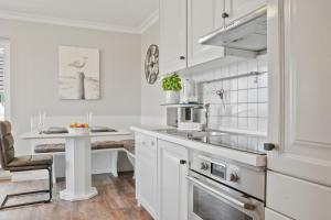a kitchen with white cabinets and a sink and a table at Gurtdeel Meerluft-Suite in Hörnum +5 photos