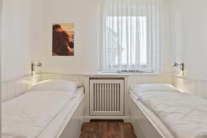 a white room with two beds and a window at Gurtdeel Meerluft-Suite in Hörnum