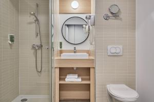 a bathroom with a sink and a toilet and a mirror at Appart'hôtel Odalys City - Lyon Centre Confluence in Lyon