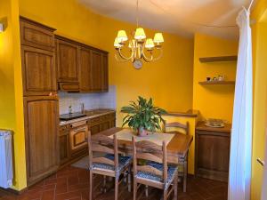 una cucina con tavolo in legno, sedie e lampadario pendente di La terrazza sul Tetto a San Marcello Pistoiese