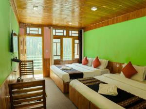 two beds in a room with green walls at Venky's Place in Jibhi