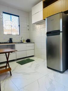 a kitchen with a stainless steel refrigerator and a table at Casa Cordelia Mangaratiba Centro in Mangaratiba