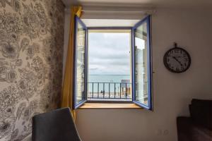 a window with a clock and a view of the ocean at La Brise- Joli T2 rénové - Vue Mer - 1 chambre in Cancale +8 photos