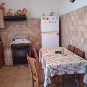 a kitchen with a table and a white refrigerator at Ikarian Family Cottage, Ikaria Droutsoulas in Akamatra