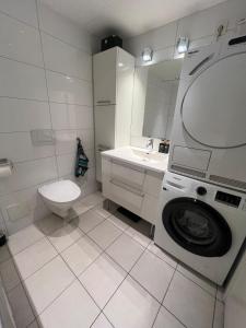 a white bathroom with a washing machine and a toilet at Spacious apartment with sea-view and sunset in Oslo +14 photos