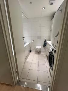 a bathroom with a toilet and a washing machine at Spacious apartment with sea-view and sunset in Oslo