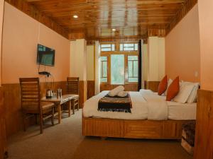 a bedroom with a bed and a table and a television at Venky's Place in Jibhi