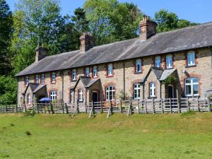 an old brick building with a fence in front of it at 3 Railway Cottages in Long Marton