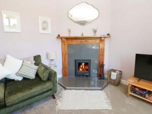 a living room with a fireplace and a green couch at 3 Railway Cottages in Long Marton
