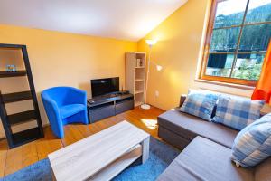 a living room with a couch and a blue chair at Villa Aspen in Demanovska Dolina