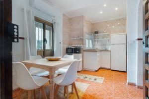 a kitchen with a wooden table and white chairs at Casa Catalán in Carmona