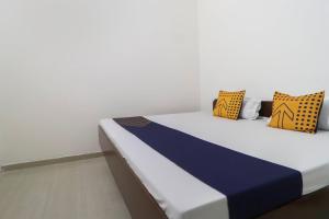 ein Bett mit blauen und gelben Kissen darauf in der Unterkunft Hotel O MCK Rooms in Rūpnagar