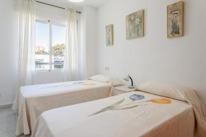 two beds in a room with a window at Morasol in El Campello