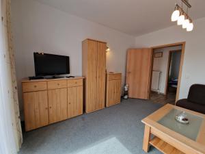 a living room with a flat screen tv on a wooden cabinet at Ferienwohnung "Fehn-Moor" 95156 in Rhauderfehn +10 photos