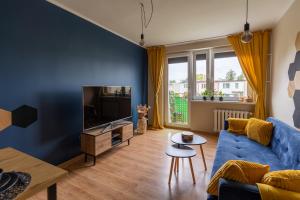 a living room with a blue couch and a tv at Hexagon Studio Comfort in Gdańsk