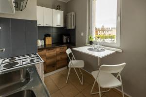 a kitchen with white chairs and a table and a window at Hexagon Studio Comfort in Gdańsk
