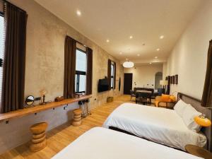 a bedroom with two beds and a living room at Spring Stay Inn 春眠 不覺曉 in Tainan