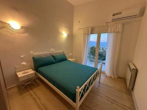a bedroom with a bed with green sheets and a window at La maison des oliviers in Kiáton