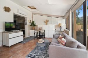 a living room with a couch and a tv at Hôtel La Nartelle in Sainte-Maxime