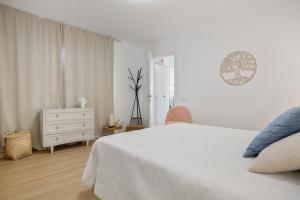 a white bedroom with a white bed and a dresser at Villa Dharma- Casa Con Encanto in La Oliva