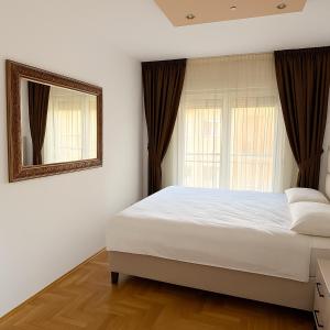 a bedroom with a white bed and a mirror at Casa Verde LLS in Budva