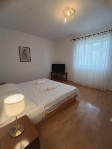 Un dormitorio con una gran cama blanca y un televisor. en Apartmani Marijan Zavala-prizemlje, en Zavala 3 fotos más