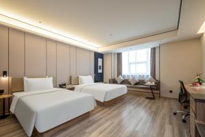 杭州杭州下沙亚朵酒店的一间酒店房间，配有两张床和一张沙发