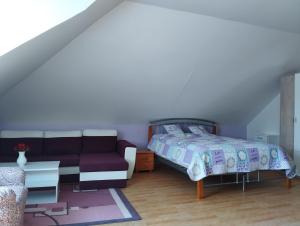 a bedroom with a bed and a couch at Apartmán Greenhouse in Budikovany