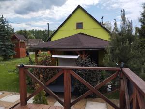a yellow house with a porch in a yard at Apartmán Greenhouse in Budikovany