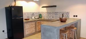 a kitchen with a black refrigerator and wooden cabinets at Amada Penida Villa in Nusa Penida +21 photos
