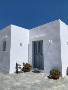 a white building with a black door and some plants at Cycladic Lodge Sifnos in Apollonia