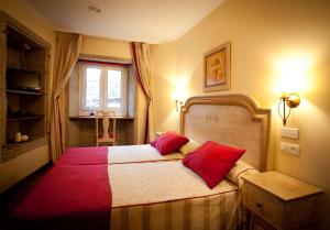 1 dormitorio con 1 cama con 2 almohadas rojas en Hotel Fonte de San Roque, en Santiago de Compostela