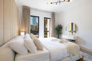 a white bedroom with a large bed with a window at Luxury 2BR Apartment in Downtown Dubai Burj Khalifa View Walk to Dubai Mall By ĀYA Boutique in Dubai