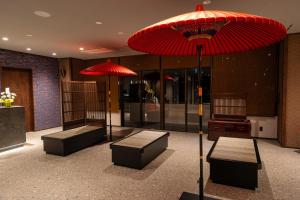 a room with two benches and a red umbrella at KAMENOI HOTEL Kusatsu Yubatake in Kusatsu