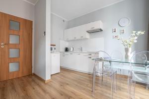 a kitchen and dining room with a glass table and chairs at Naptun Old Town by Alqueen Apartments in Gdańsk +20 photos