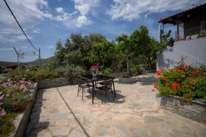 a patio with a table and chairs and flowers at Villa PAPADATES ARTEMIS in Barbaliáki