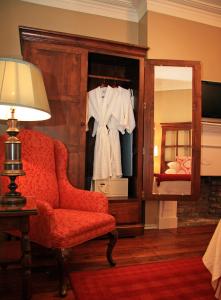 a bedroom with a red chair and a mirror at The Marshall House, Historic Inns of Savannah Collection in Savannah