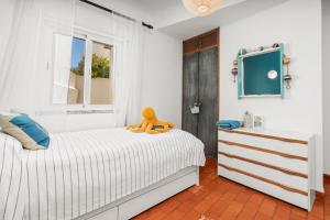 a white bedroom with a teddy bear sitting on a bed at Casa Indie in Burgau