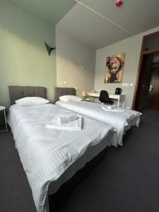 two beds are in a room with a desk at Hotel Vento in Ventspils