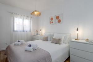 a white bedroom with a large white bed with towels on it at Nest by the Lagoa, Carvalhal in Carvalhal