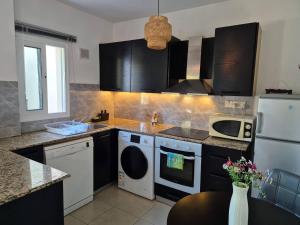 una cocina con armarios negros y electrodomésticos blancos en Olymbos Garden Apartment IV, en Ayia Napa