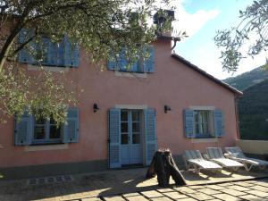 Casa de color rosa con sillas y ventanas con persianas azules en Casa Aquarela, en Cogorno