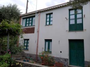 a white house with green doors and flowers at La casa di Filippo e Filippa in Gioiosa Marea +10 photos