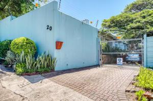 Muthaiga Stays - Studio Venue في ديربان: مبنى ازرق مع بوابة في ساحة