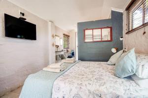 Muthaiga Stays - Studio Venue في ديربان: غرفة نوم بها سرير كبير وتلفزيون بشاشة مسطحة