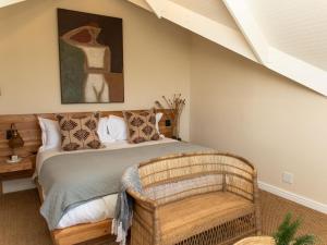 a bedroom with a bed with a chair and a painting at Little Villa by Ideas Cartel in Hermanus