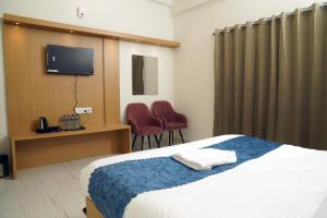 NalmathaHotel Royal Heriage的一间带床和电视的酒店房间