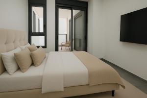 a bedroom with a white bed and a flat screen tv at דירת נופש באכזיב על הים in Nahariyya