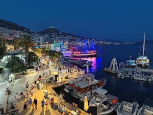 a group of people walking around a marina at night at Sun N Blue Hotel in Sarandë